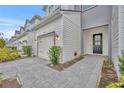 Front entry and walkway of townhome with gray and white siding and paver driveway at 1479 Brookdale Ct, Oviedo, FL 32765