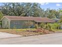 Green house with brown roof, and mature trees at 1613 Oriole Ave, Orlando, FL 32803