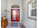 Front entry with red door, decorative rug and wooden cabinet at 17478 Se 115Th Terrace Rd, Summerfield, FL 34491