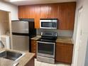 Kitchen features stainless steel appliances, wooden cabinets, granite counters, and tiled floors at 11538 Westwood Blvd # 226, Orlando, FL 32821