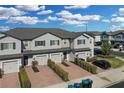 An aerial view showing gray townhomes in a neighborhood, with brick driveways and landscaping under a blue sky at 12067 White Wave Pt, Orlando, FL 32828