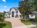 Two story home with a brick driveway, a tile roof, and lush landscaping at 408 Chelsea Ave, Davenport, FL 33837