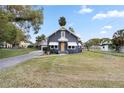 Gray house with white accents, a wooden door, and a spacious lawn at 119 Leon Ave, Deland, FL 32720