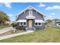 Gray house with white accents, a wooden door, and a spacious lawn at 119 Leon Ave, Deland, FL 32720