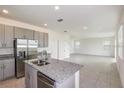 Modern kitchen with gray cabinets, granite countertops, and stainless steel appliances at 267 Bottle Brush Dr, Haines City, FL 33844