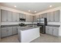 Spacious kitchen featuring gray cabinets, granite island, and stainless steel appliances at 267 Bottle Brush Dr, Haines City, FL 33844