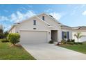 Tan house with a two-car garage, landscaping, and a blue door at 4530 Tahoe Cir, Clermont, FL 34714