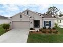 Beige house with blue shutters, two-car garage, and neatly landscaped yard at 4530 Tahoe Cir, Clermont, FL 34714