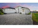 White house with a three-car garage and paver driveway at 118 River Ln, Ormond Beach, FL 32176