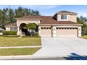 Two-story home with tan stucco, a three-car garage, and well maintained landscaping at 13132 Coldwater Loop, Clermont, FL 34711