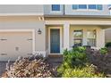 Front entryway with dark blue door, landscaping, and brick walkway at 2530 Domenico Paul Way, Orlando, FL 32810