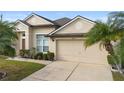 Tan one-story house with palm trees, two-car garage, and landscaped lawn at 2920 River Birch Dr, Kissimmee, FL 34741