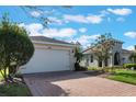 White two-car garage with paver driveway and landscaping at 560 Presido Park Pl, Kissimmee, FL 34759