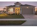 Two-story house exterior at dusk, with landscaping and a three-car garage at 8575 Hempstead Way, Mount Dora, FL 32757