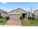 One story house with a two car garage, brick driveway, and landscaping at 9653 Early Loop, Groveland, FL 34736