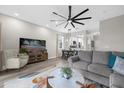 Open living space with gray sectional sofa, ceiling fan, and kitchen view at 100 Napoli Dr, Davenport, FL 33897