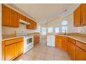 Kitchen with wood cabinets, white appliances, and tile flooring at 108 Strait Dr, Davenport, FL 33897