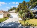 Tan house with white garage door, palm trees, and manicured lawn at 3427 Kayla Cir, Oviedo, FL 32765