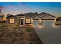 Two-story house with stone accents, three-car garage, and a large driveway at dusk at 41289 County Road, 452, Leesburg, FL 34788