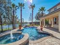 Relaxing pool and spa area with a patio, lake view, and lush landscaping at 14442 Avenue Of The Rushes, Winter Garden, FL 34787