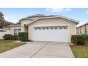 Tan one-story house with a two-car garage and landscaped yard at 2220 Wyndham Palms Way, Kissimmee, FL 34747