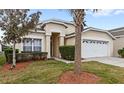 Tan one-story house with a two-car garage and palm trees at 2220 Wyndham Palms Way, Kissimmee, FL 34747