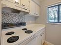 Kitchen features white cabinets, mosaic backsplash, and an electric range at 127 Springwood Cir # A, Longwood, FL 32750
