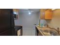 Eat-in kitchen with wood cabinets, black appliances, and tile floor at 1695 Lee Rd # A209, Winter Park, FL 32789