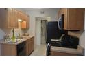 Galley kitchen with wood cabinets, black appliances, and tile floor at 1695 Lee Rd # A209, Winter Park, FL 32789