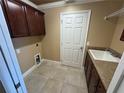 Functional laundry room with cabinetry, sink, and tile flooring at 2544 Ashville Ave, The Villages, FL 32162