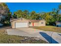 Tan single story house with a red door, attached garage, and a large yard at 5711 Bolling Dr, Orlando, FL 32808