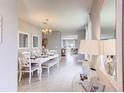 Elegant dining room with white table and chairs, chandelier, and view to the kitchen at 1593 Bull Hill Rd, Kissimmee, FL 34744