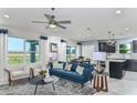 Open living room and kitchen with teal sofa, white chairs, and dark cabinets at 2440 Belle Haven Way, Davenport, FL 33896