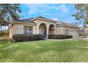 Landscaped yard with a beige house and two car garage at 268 Heatherbrooke Cir, Oviedo, FL 32765