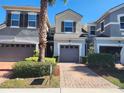 Exterior view of a two-story townhome with gray siding, two-car garage, and landscaped front yard at 3656 Brighton Park Cir, Orlando, FL 32812