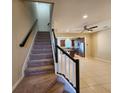 Carpeted staircase with dark wood railing leading to an open living area and kitchen at 3656 Brighton Park Cir, Orlando, FL 32812