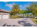 Driveway with paver surface leading up to a three-car garage, with mature landscaping, and a pond nearby at 15041 Gaulberry Run, Winter Garden, FL 34787