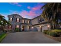 Beautiful exterior view of a two-story home with stone accents, landscaping, and a paver driveway at dusk at 15041 Gaulberry Run, Winter Garden, FL 34787