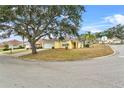 Yellow house on a corner lot with a large tree and neighborhood view at 1685 Waterview Loop, Haines City, FL 33844