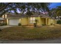 House exterior at dusk, yellow siding, attached garage, and well-manicured lawn at 1685 Waterview Loop, Haines City, FL 33844