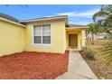 House entrance with yellow siding, brown door, and red mulch landscaping at 1685 Waterview Loop, Haines City, FL 33844