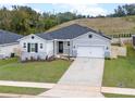 One-story home with gray siding, landscaping, and a driveway at 1933 Burgundy Dr, Minneola, FL 34715