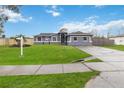 Newly built home with gray exterior, green lawn, and a driveway at 3662 Mohawk Dr, Mount Dora, FL 32757