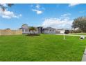 Gray house with a fenced yard, palm trees, and a large green lawn at 3662 Mohawk Dr, Mount Dora, FL 32757