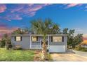 Gray house with white garage door, landscaping, and palm trees at dusk at 4862 Indialantic Dr, Orlando, FL 32808