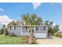 Gray house with white garage door, landscaping, and palm trees at 4862 Indialantic Dr, Orlando, FL 32808