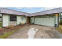 Front view of a charming light green house with a metal roof and attached garage at 628 Twin Oaks Cir, Daytona Beach, FL 32117