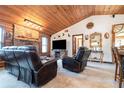 Cozy living room with a stone fireplace, leather furniture, and wood ceilings at 628 Twin Oaks Cir, Daytona Beach, FL 32117