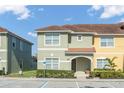 Two-story townhome with light green and yellow exterior, landscaping, and parking at 8925 Candy Palm Rd, Kissimmee, FL 34747