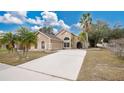 This attractive home showcases a lush yard, palm trees, and a long driveway leading to an attached two car garage at 905 Hatteras Ave, Minneola, FL 34715